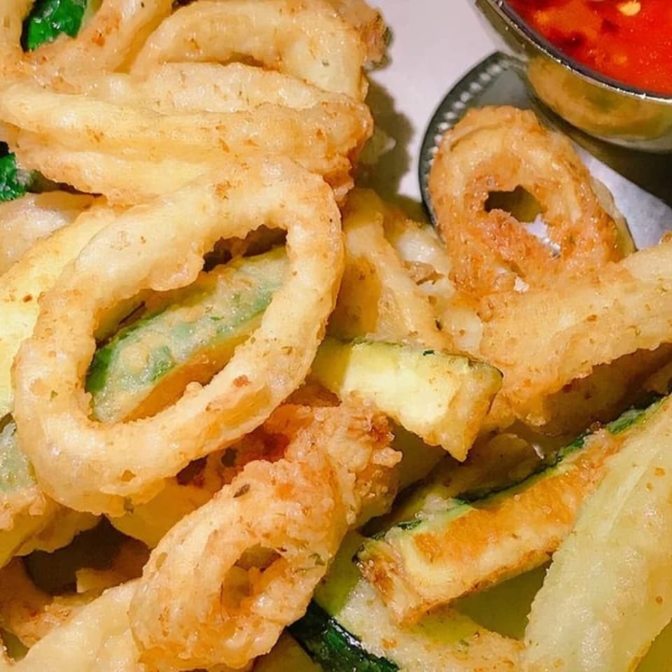 Crispy fried calamari and zucchini slices with a side of red dipping sauce at Carino's.