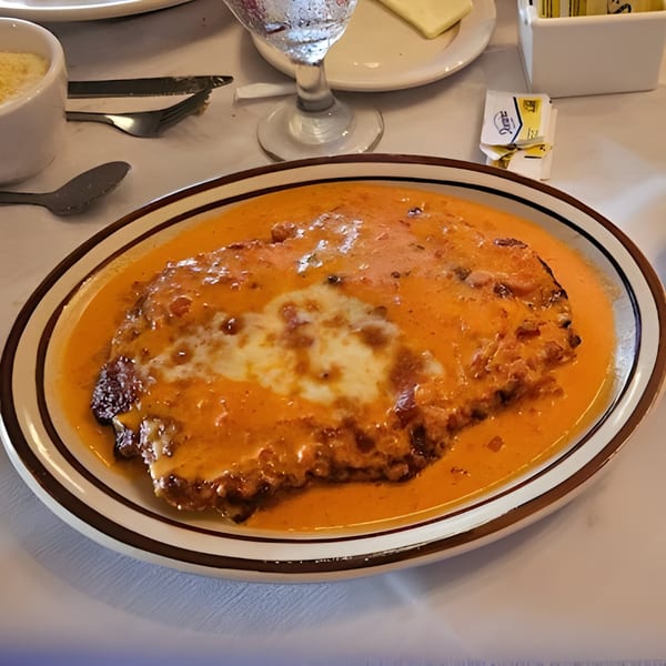 Carino's Northern Italian Cuisine's chicken parmesan, covered in a creamy orange sauce with melted cheese.
